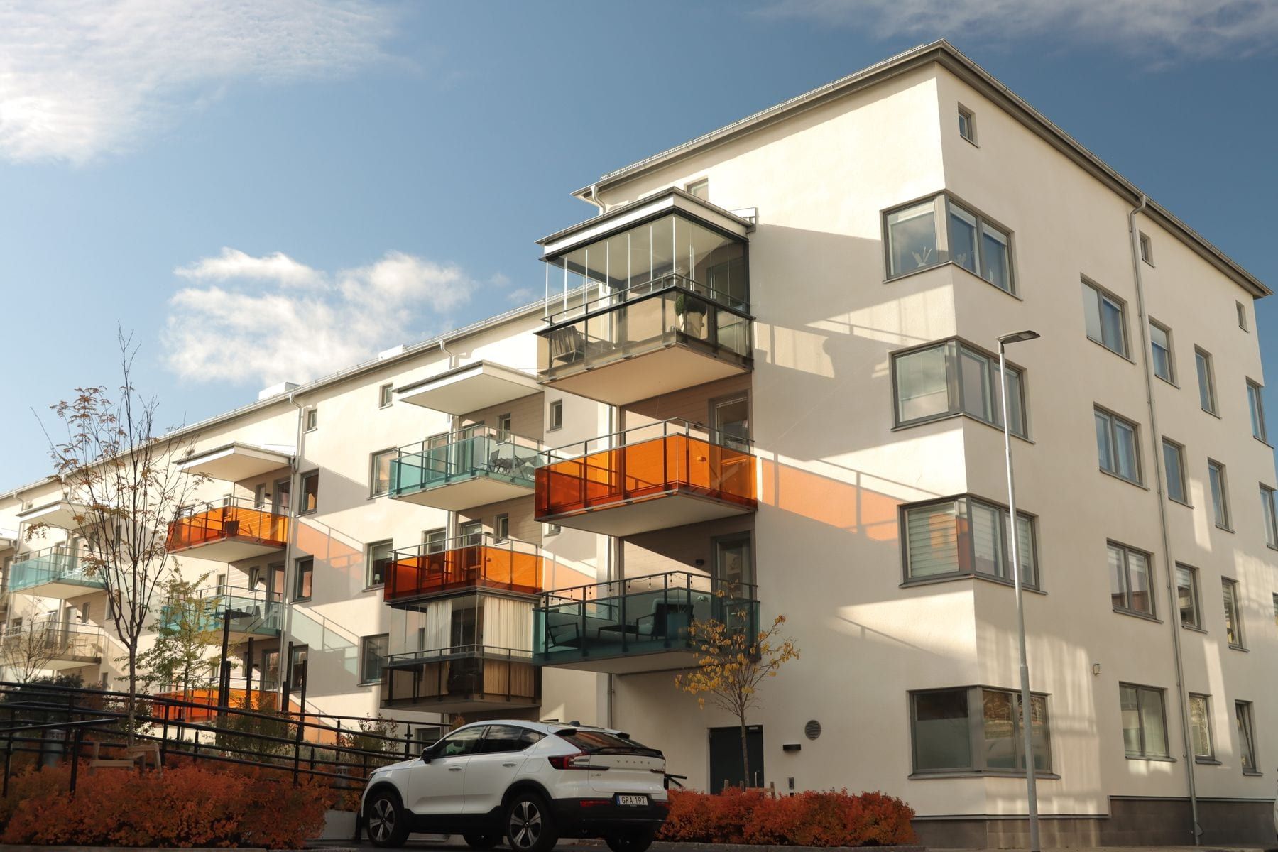 Ljust flerbostadshus med balkonger mot blå himmel