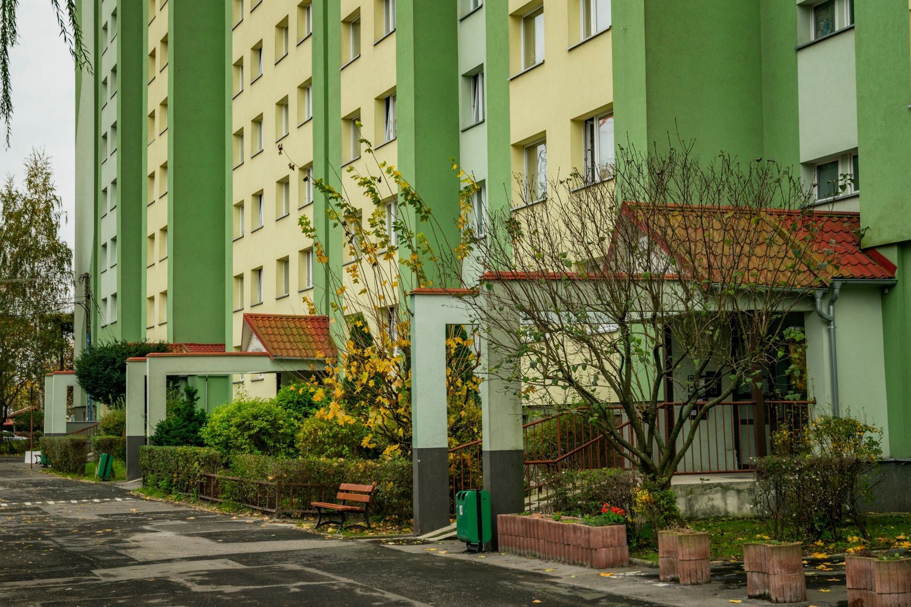 Green apartment buildings with a garden and benches